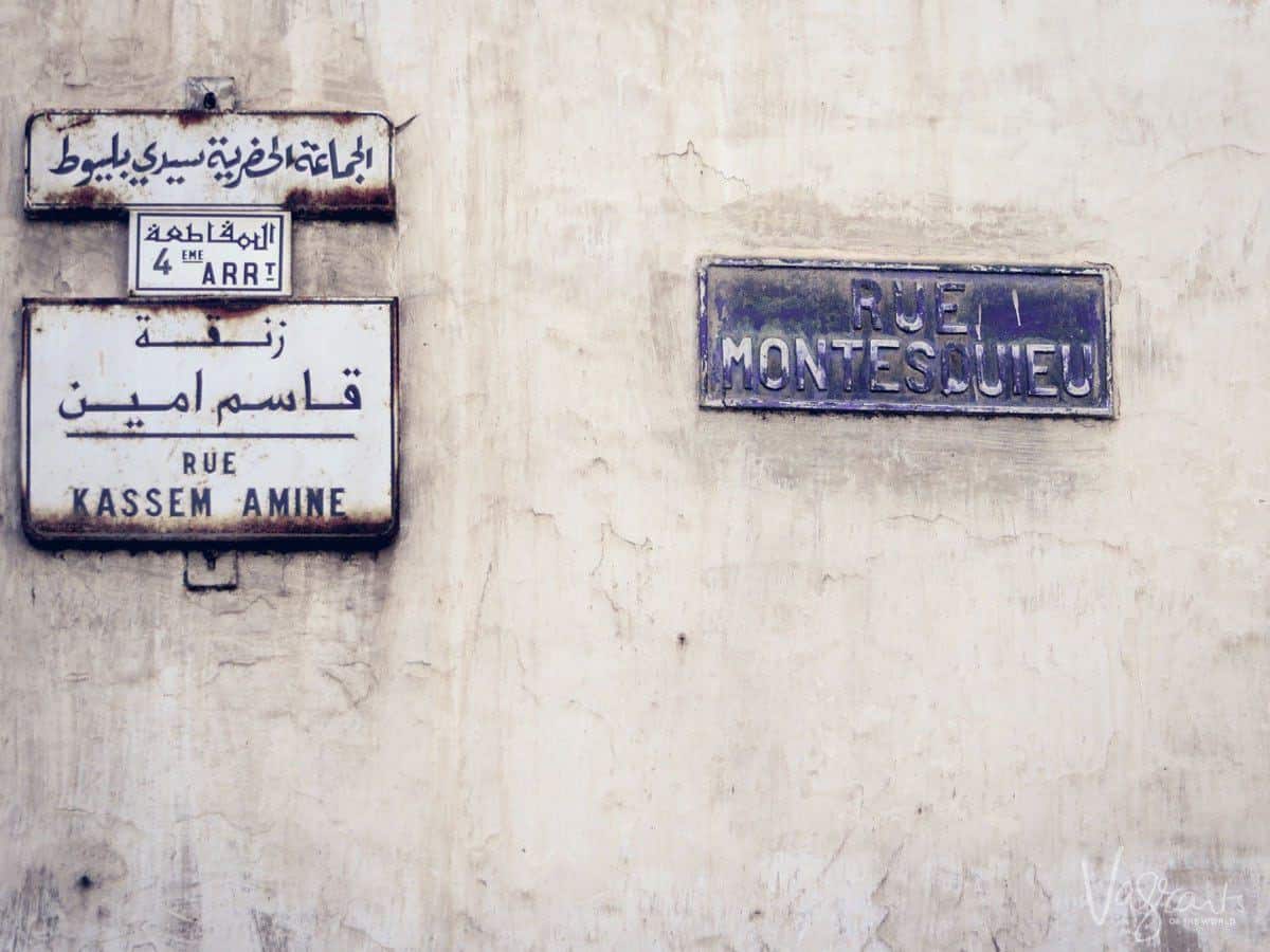 Street signs written in blue in Arabic and French on a white building in Casablanca, Morocco.
