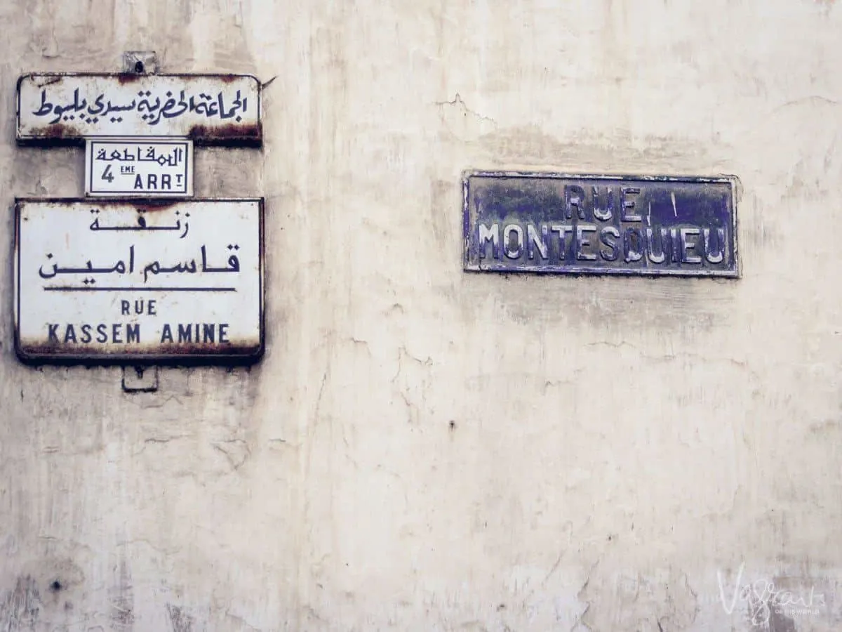 Street signs written in blue in Arabic and French on a white building in Casablanca, Morocco.
