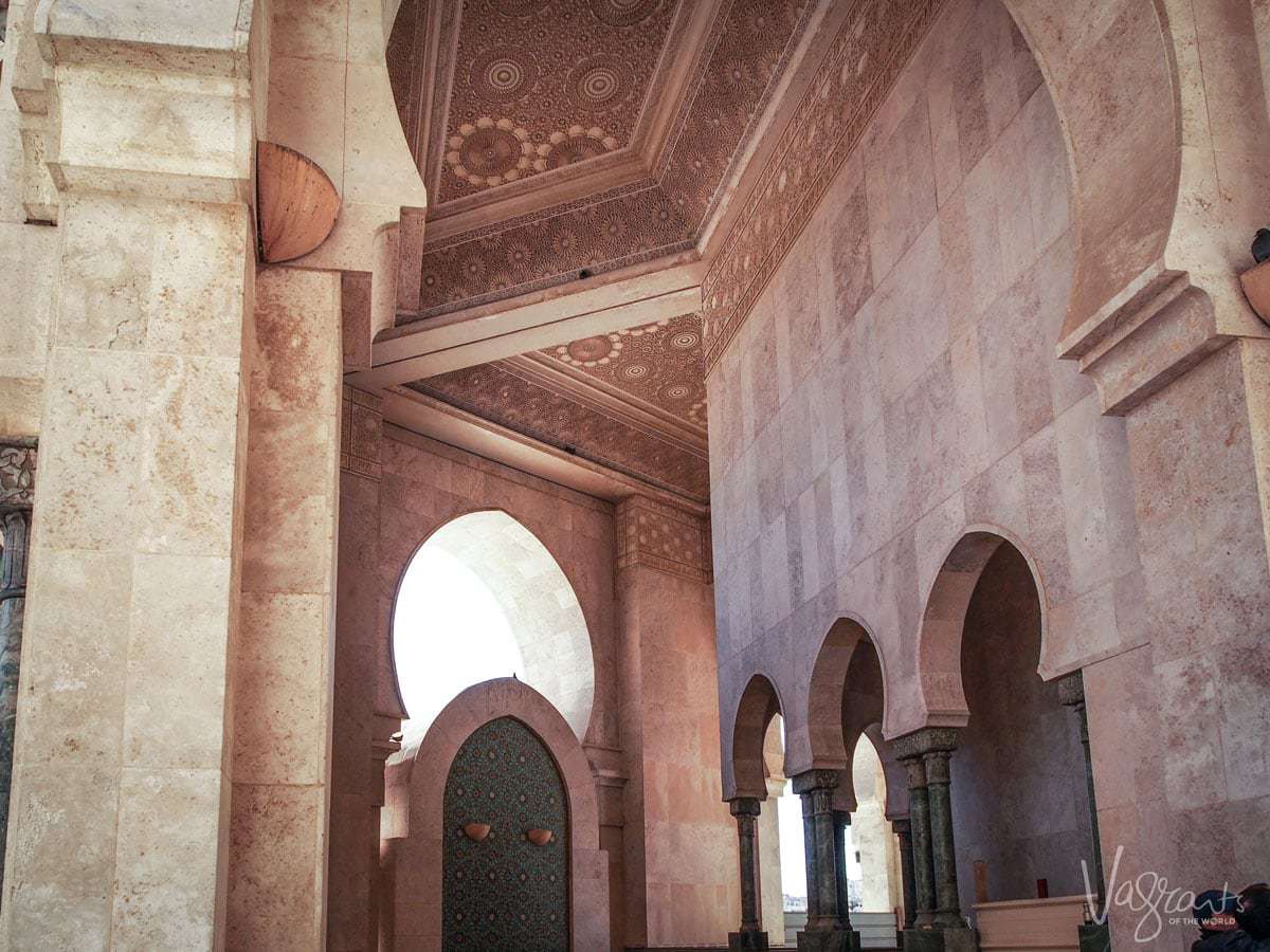 The inside of the Hassan II Mosque in Casablanca, Morocco with ornate arched doorways and decorated ceilings.