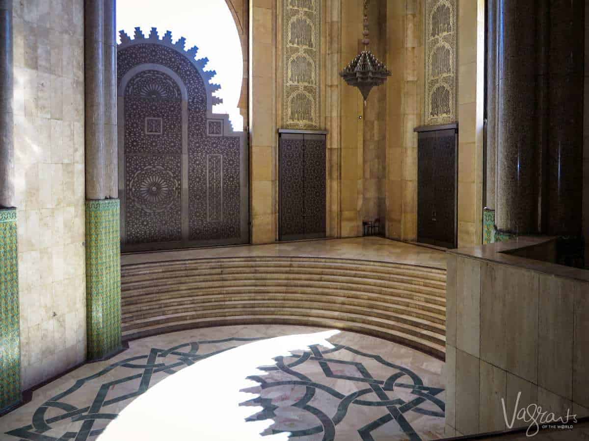 Steps inside the Mosque Hassan II  Mosque leading up to three sets of ornately decorated doors. 