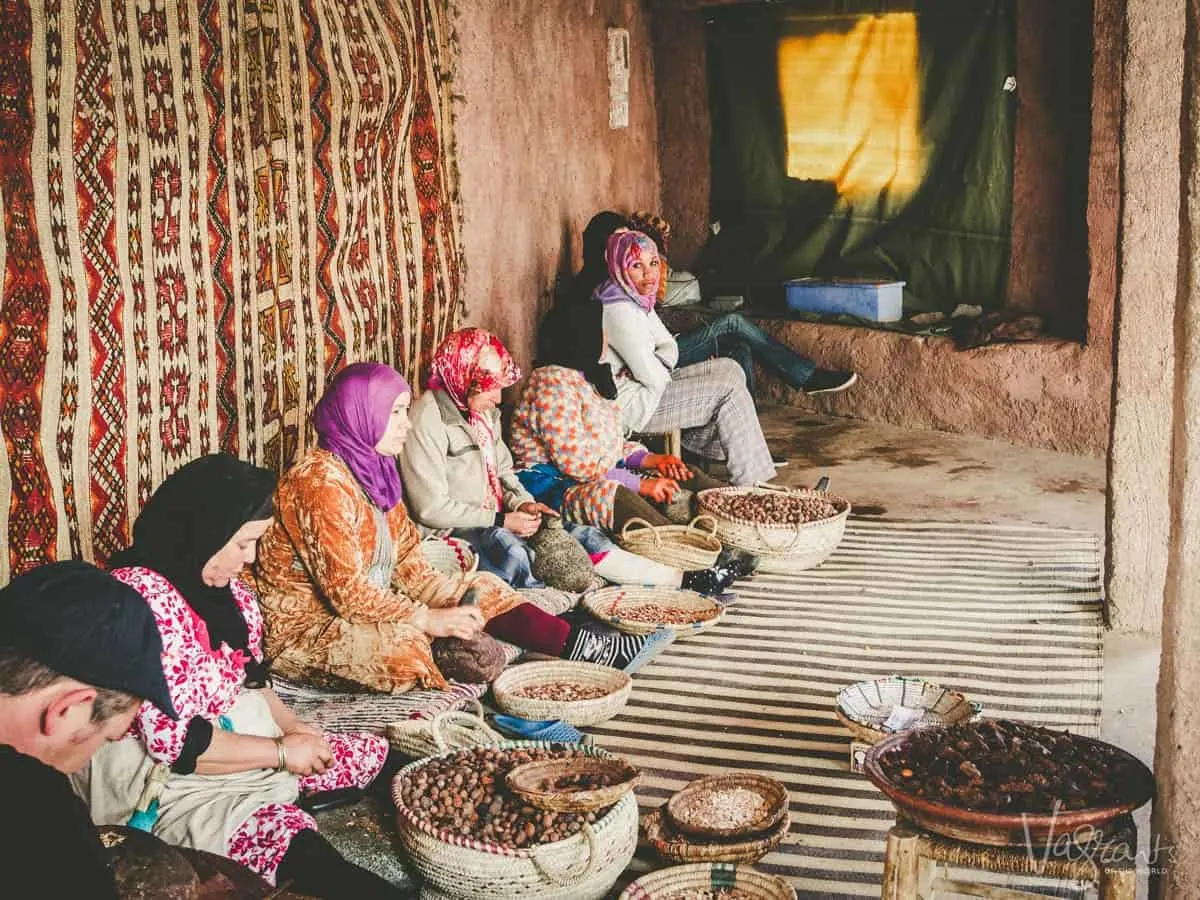 Woman sitting against a wall with large wicker baskets of coffee beans at a Womens co op Atlas Mountains Morocco