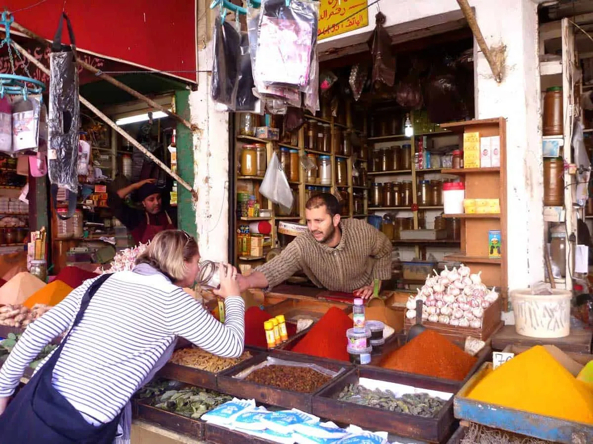 A woman leaning ove a spice counter in the Casablanca medina to smell the spices being offered by the male vendor. 