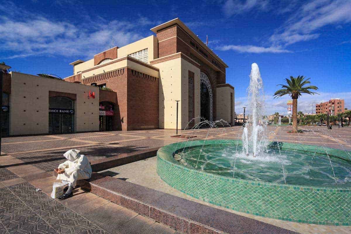 man in white garb sitting on fountain in new Town Marrakech Morocco. things to avoid in Marrakesh. Beware of scammers.