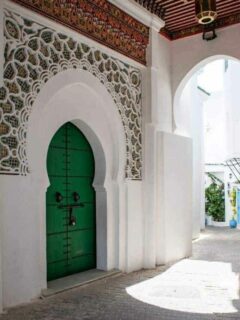Ornate green door in a white washed alley in Tangier Morocco.