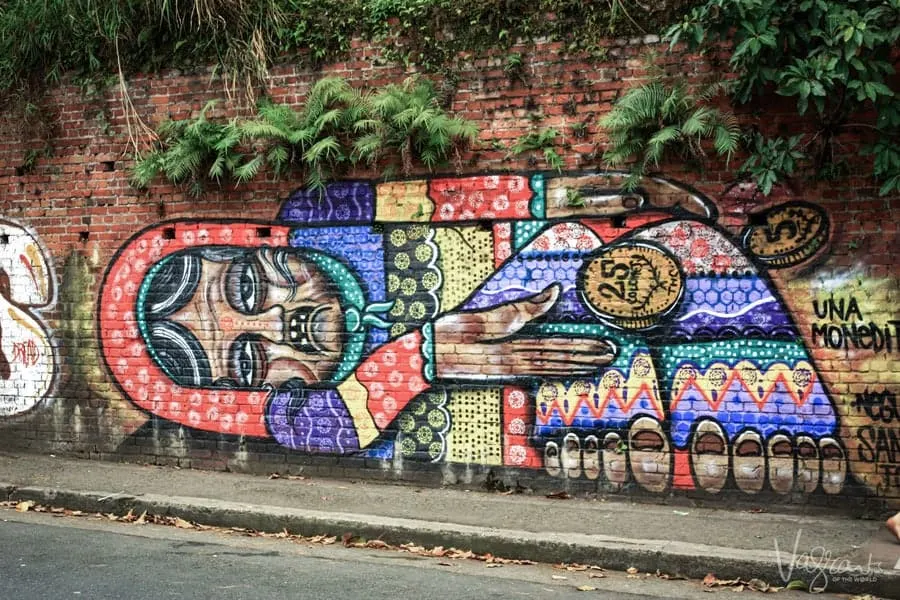 Bright street art on a brick wall with ferns growing from the top in San Jose. 