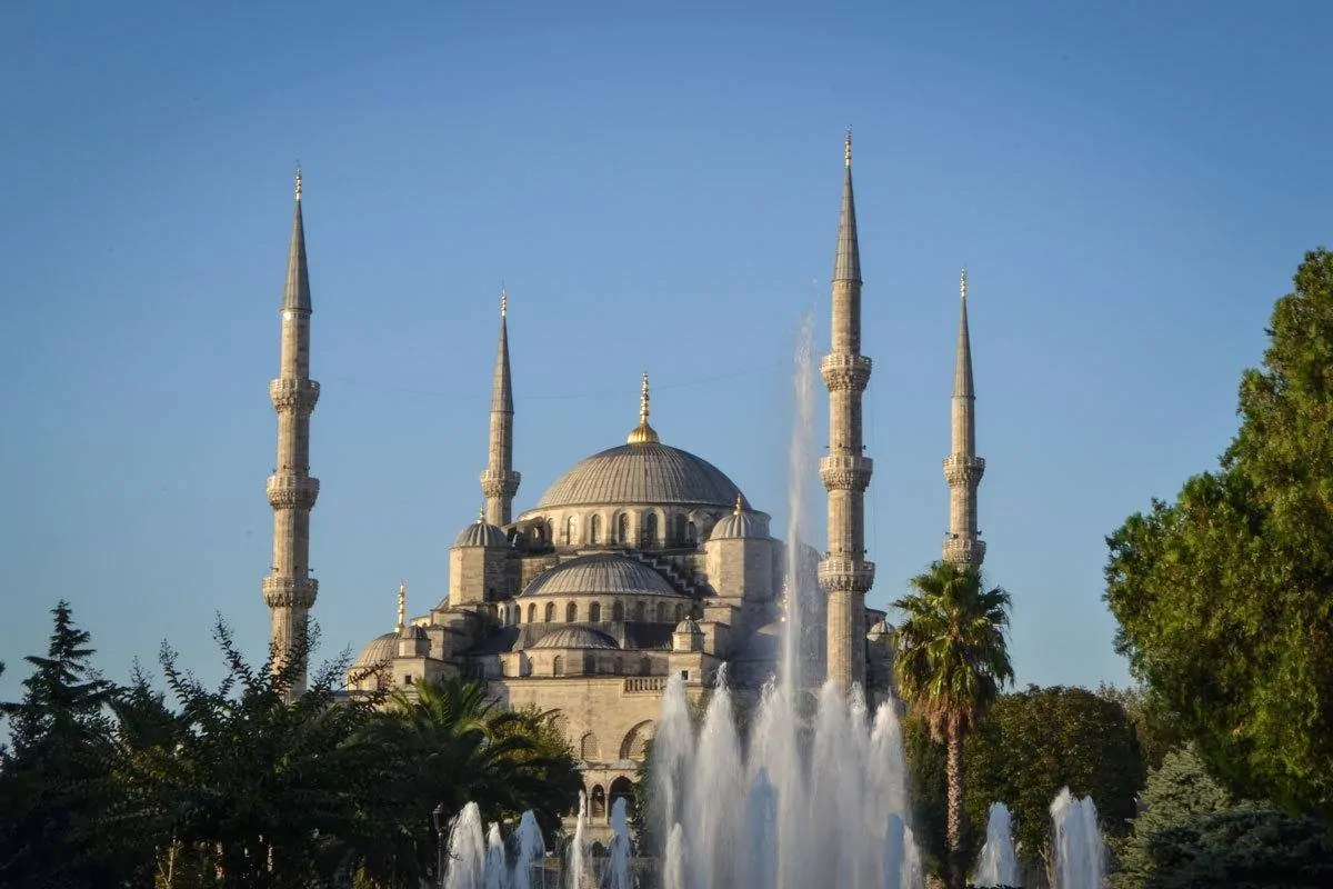 A fountain in front of the 4 spires and Blue Mosque on a clear day. 