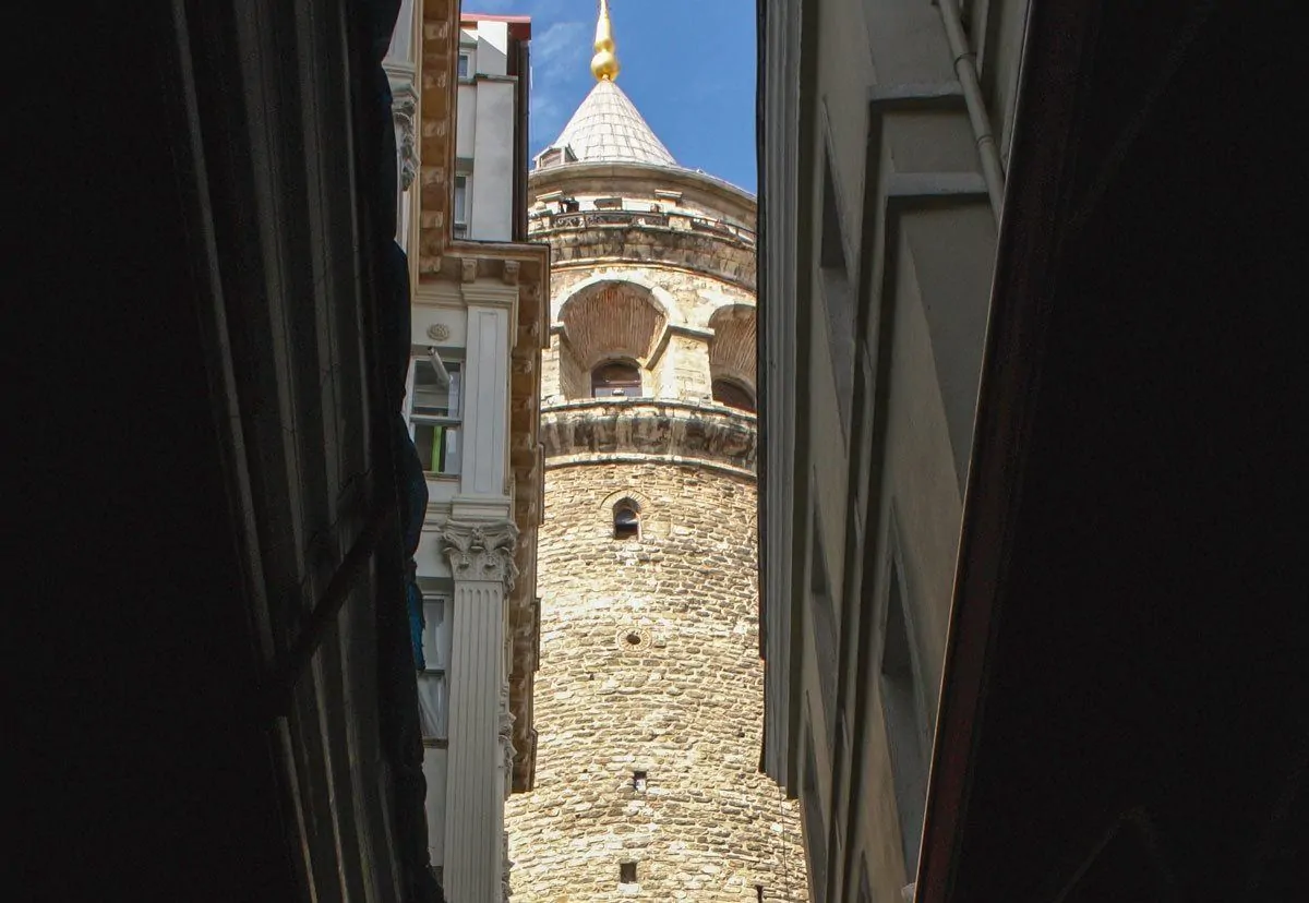 Narrow view of Galata tower between two buildings.