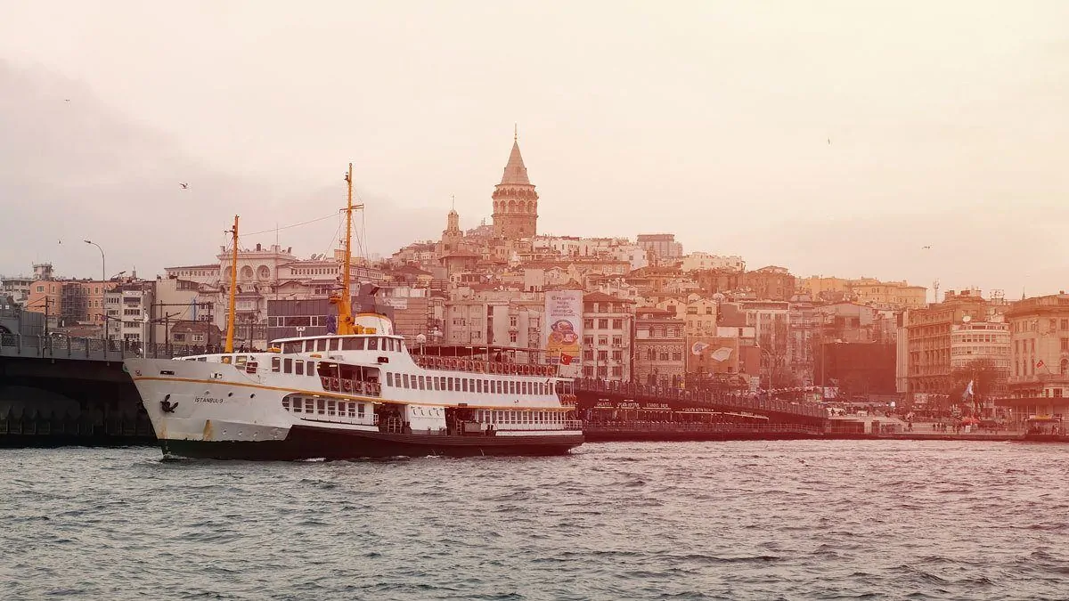 A boat on a Bosphorus river cruise in Istanbul with the city in the background at sunset. 