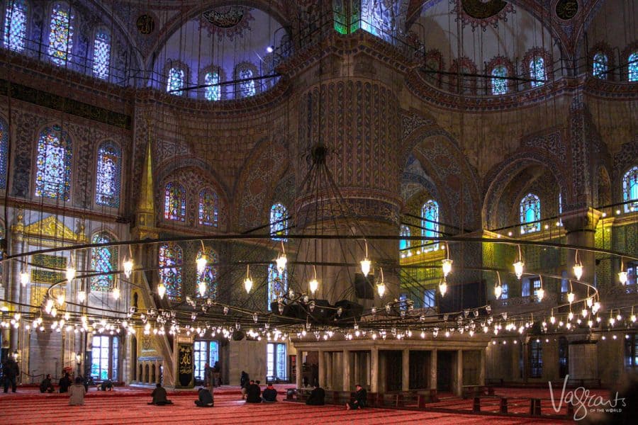 Stain glass windows look down an men praying in the Blue Mosque, in Istanbul. 