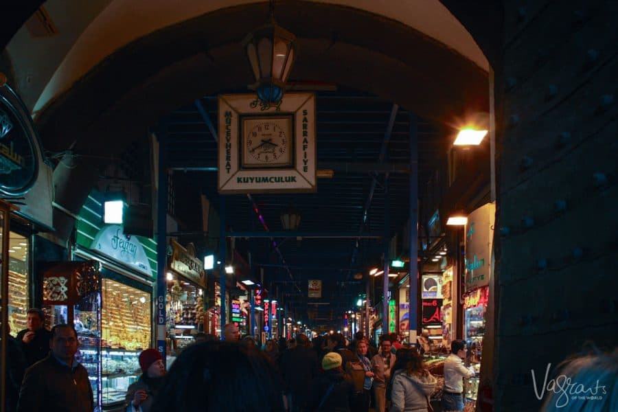 Many people fill the dark corridors of the Spice Bazaar with colourful spice stalls lining the walkways. 