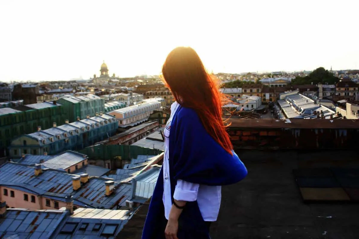 Girl standing on the roof overlooking St Petersburg at sunset. 