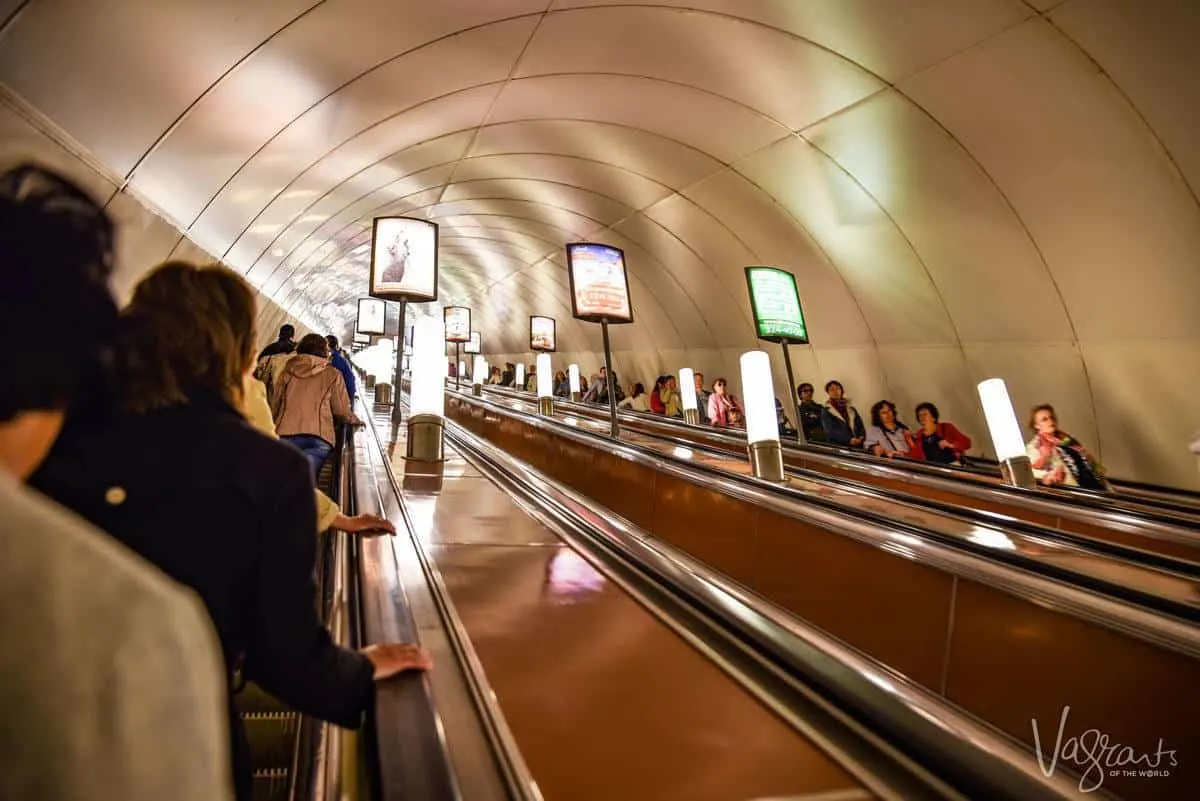 People riding the steep escalators, St Petersburg metro. Interesting things to see in St Petersburg are the metro stations