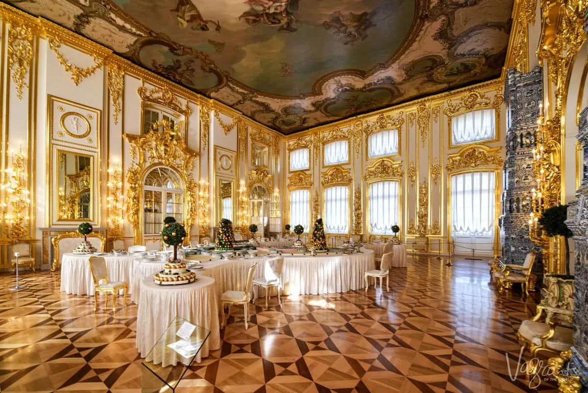 Gilded walls and windows surround the table settings for a grand meal in the Catherine Palace dining room.