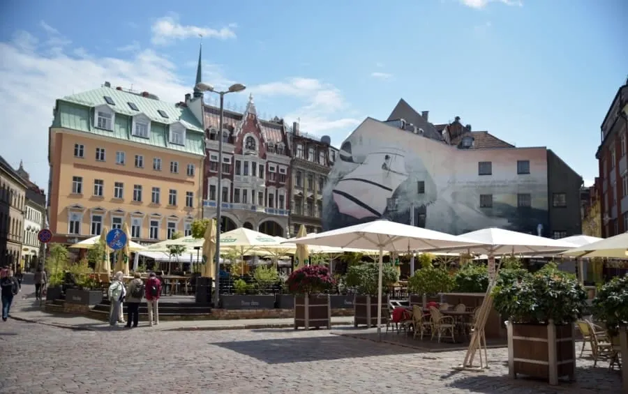 Cafes with colourful old buildings in the background in Old City Riga Latvia. There are plenty of great places to eat and drink in Riga making it a perfect city break.