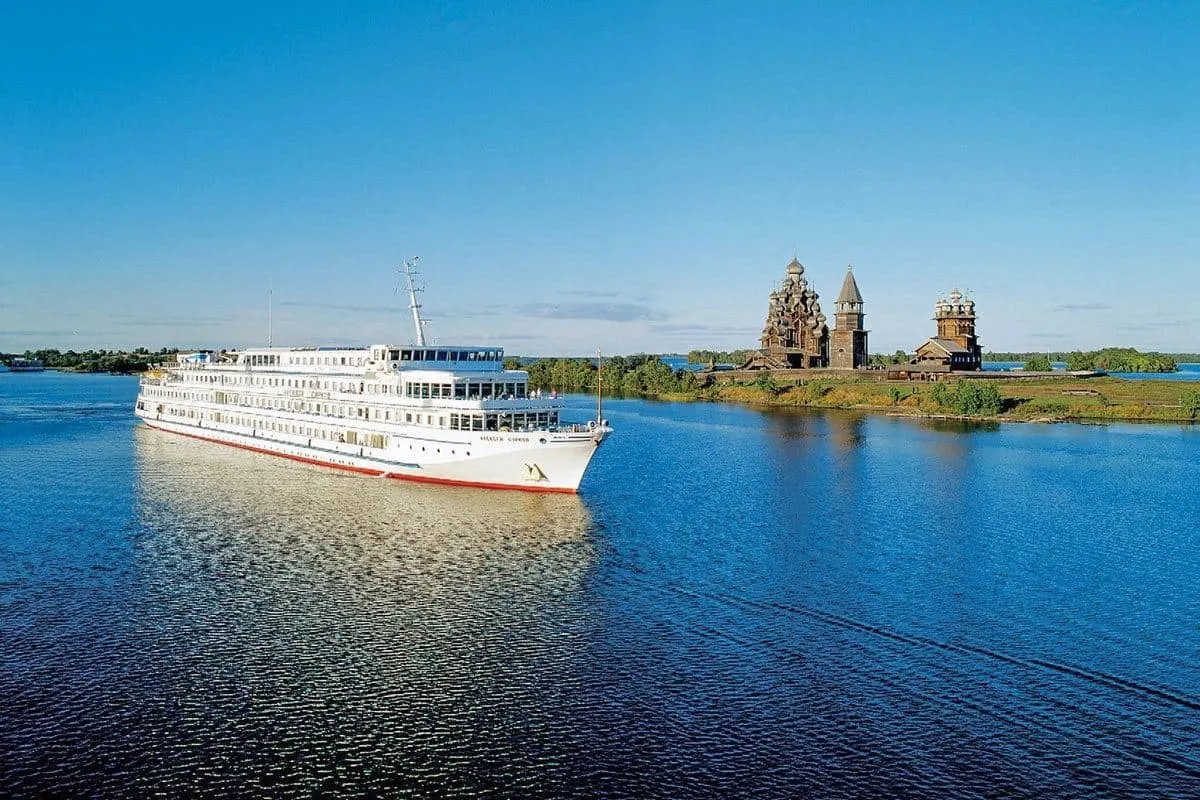 Viking river boat with temple on an island in the background.  River cruises in Russia are popular and a viking river cruise from St Petersburg to Moscow is the best way to see Russia