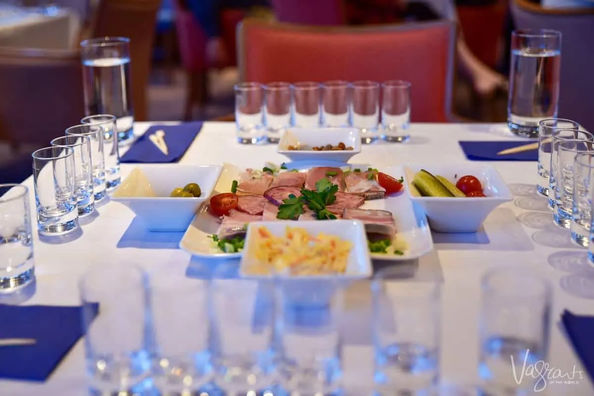 dinner setting russian style with vodka glasses and plates of russian food. fine dining is one of the many great things about a viking river cruise.