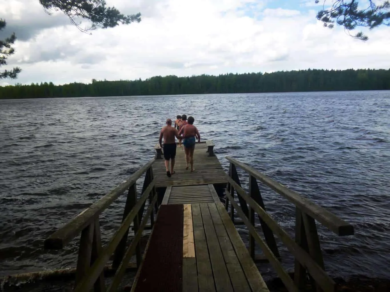 Traditional Russian Banya Mandrogy with men and women running down a pier to jump into the icy waters.