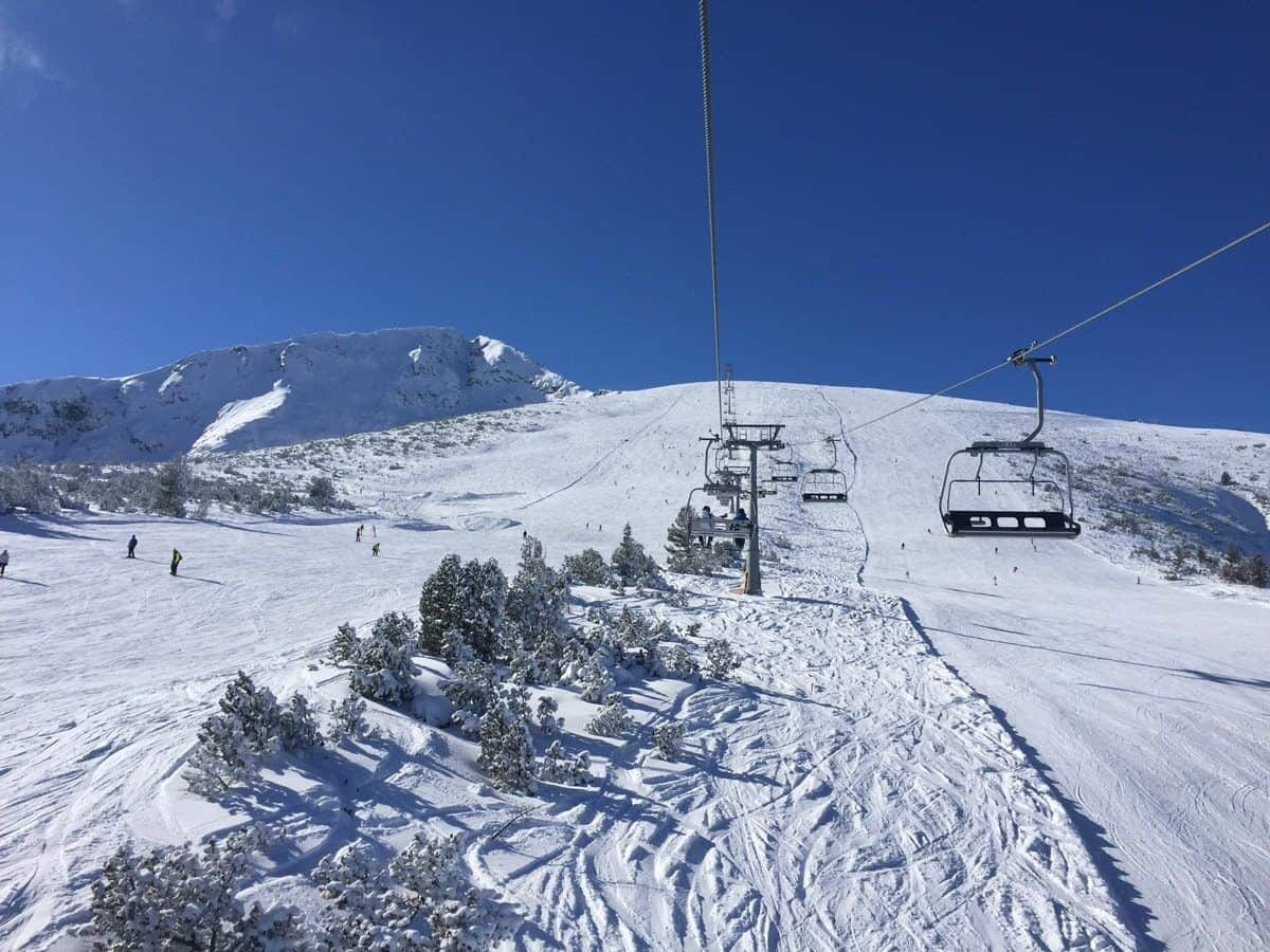 A chairlift climbing above the treeline towards the upper slopes at Bansko