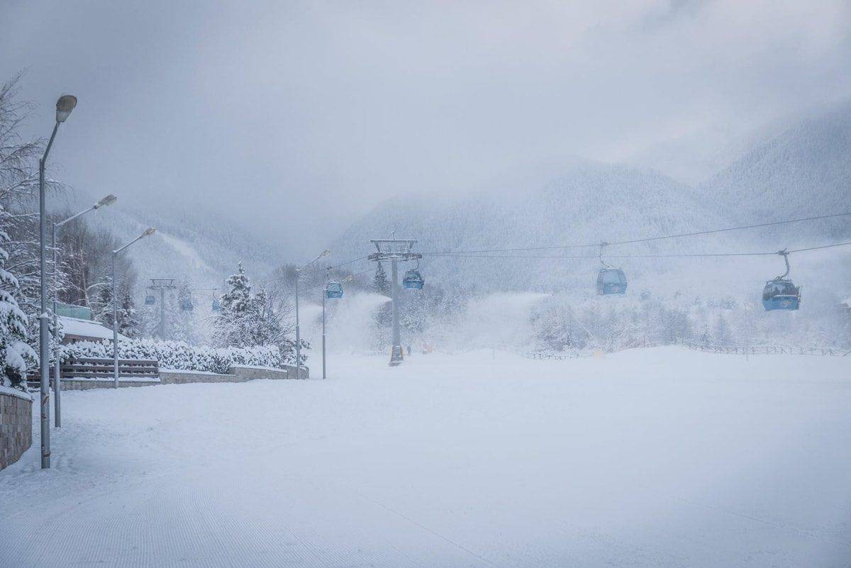 Gondola cabins climbing into low cloud on a snowy slope during ski holidays in Bulgaria