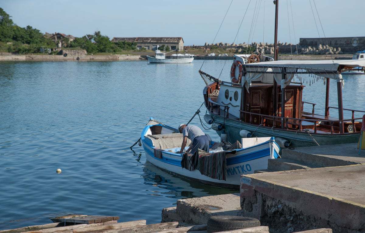 A fisherman in blue and white stripe t-shirt in his fishing boat in Sozopol Bulgaria. 