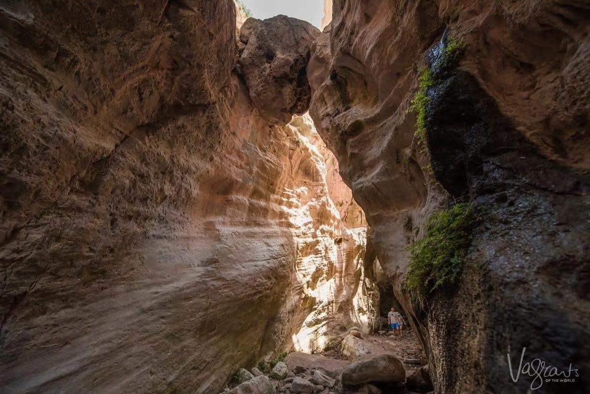 Hikers in between red rock gorge in Cyprus Akamas National Park.