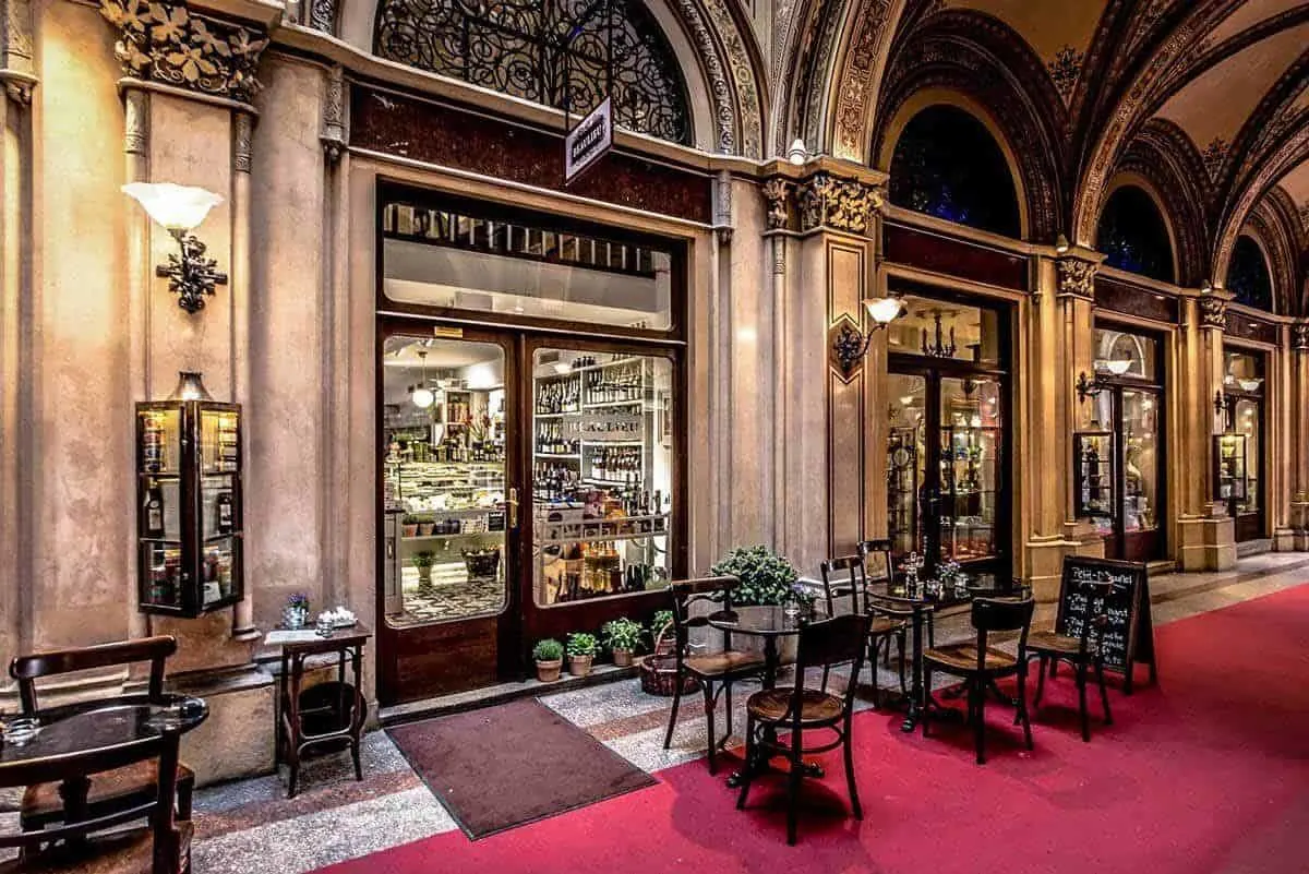 A typical Vienna coffee house with chairs and tables set up in the front.