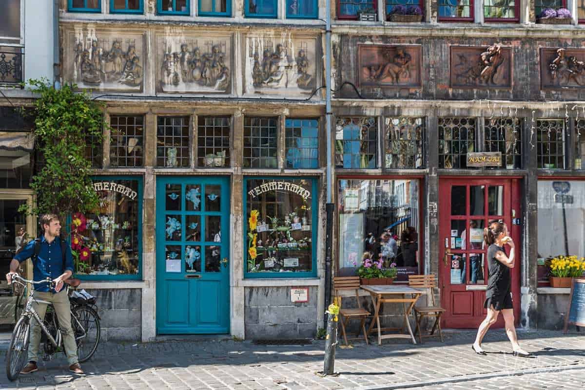 Free things to do in Ghent. People outside colourful shop fronts in Ghent, Belguim. Wandering what to do in Ghent? Take a walking tour. What are the best things to do in Belgium. Visit Ghent.