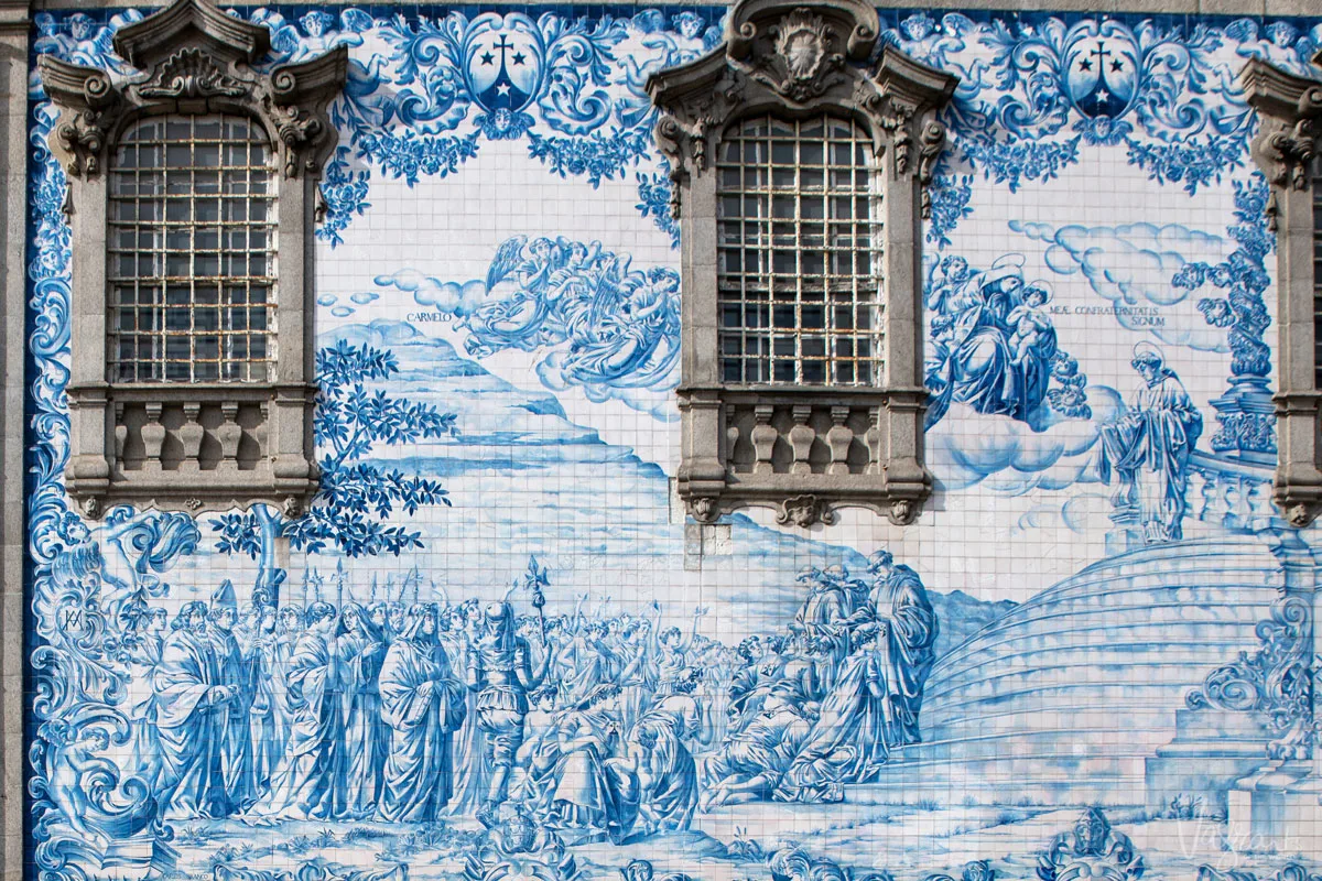 Wall of a church in Portugal with intricate blue and white azulejos tile design depicting biblical scene. 