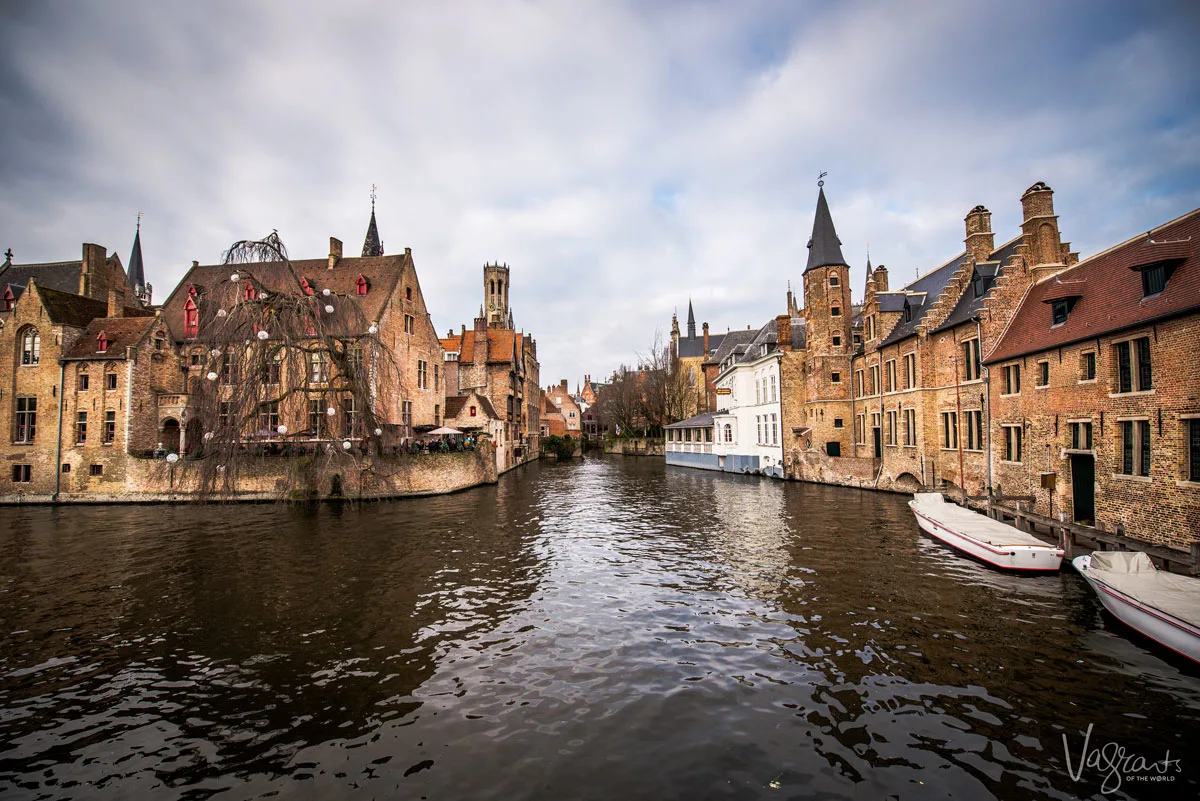 Historic building ining the Bruges Canals on a cloudy day.