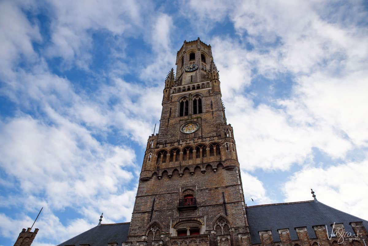 The belfry tower in bruges with blue sky and clouds.