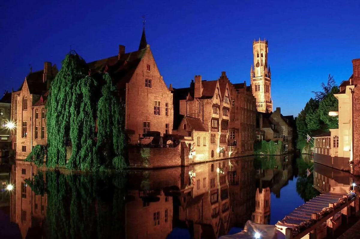 Red brick buildings lit up and reflecting in the canals in Bruges Belgium. 