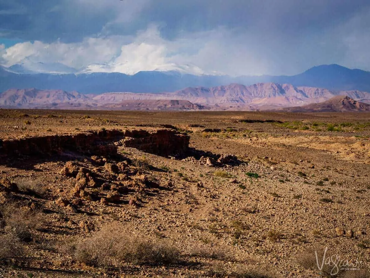 A desert scene with the mountains in the background under an angry stormy sky whilst on a moroccan road trip from Marrakech to Fez Atlas Mountains