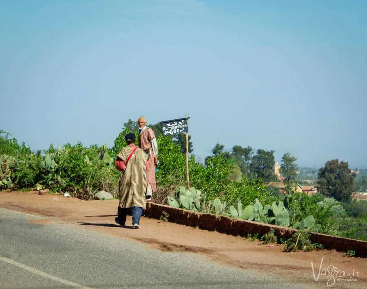 moroccan road trip, Marrakech to Fez Atlas Mountains with 2 local men on the side of the roads with cactus growing wild along the sides.