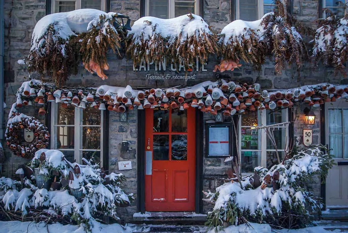A red door of a hotel framed by snow in Quebec Old Town. This is what makes Quebec one of the best places to visit in eastern Canada