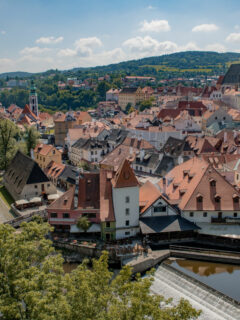 Overlooking a small medieval city with red roofs and spires on a river.