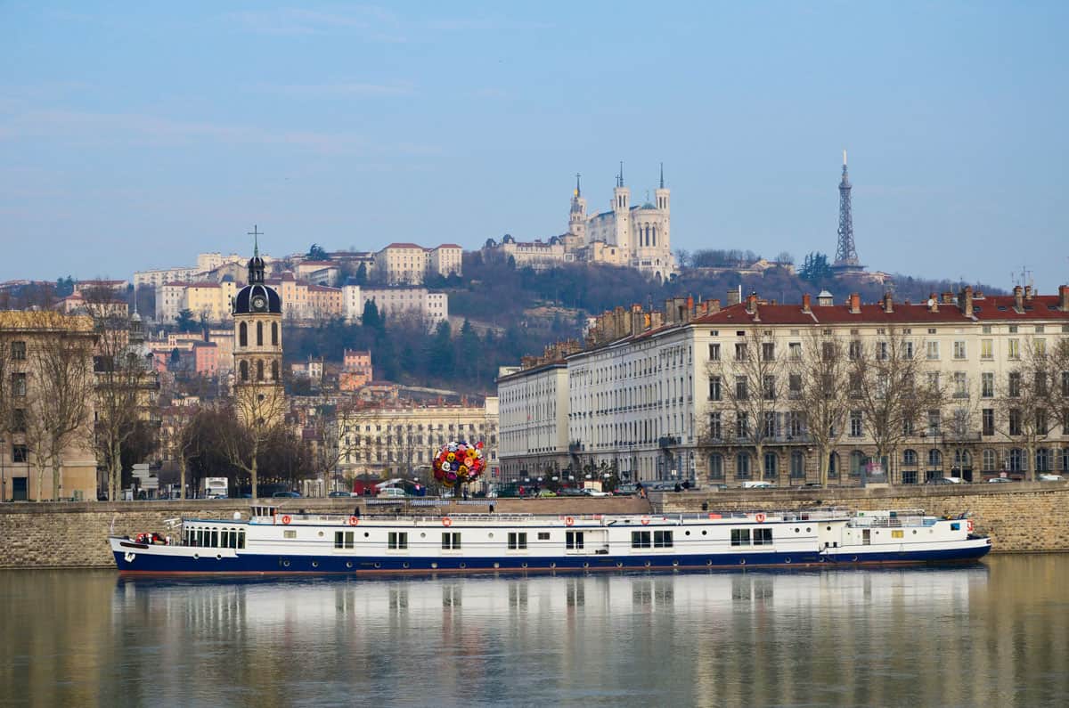 River boat on the Rhone river in front of the city of Lyon with the Lyon Eiffel tower in the distance. 