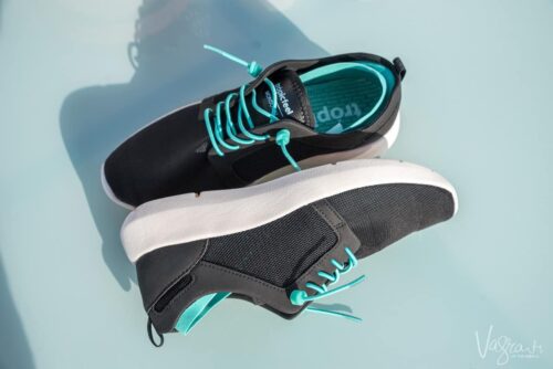 Pair of black and green Tropicfeel sneakers on a table, the best travel shoes for any travel occasion.
