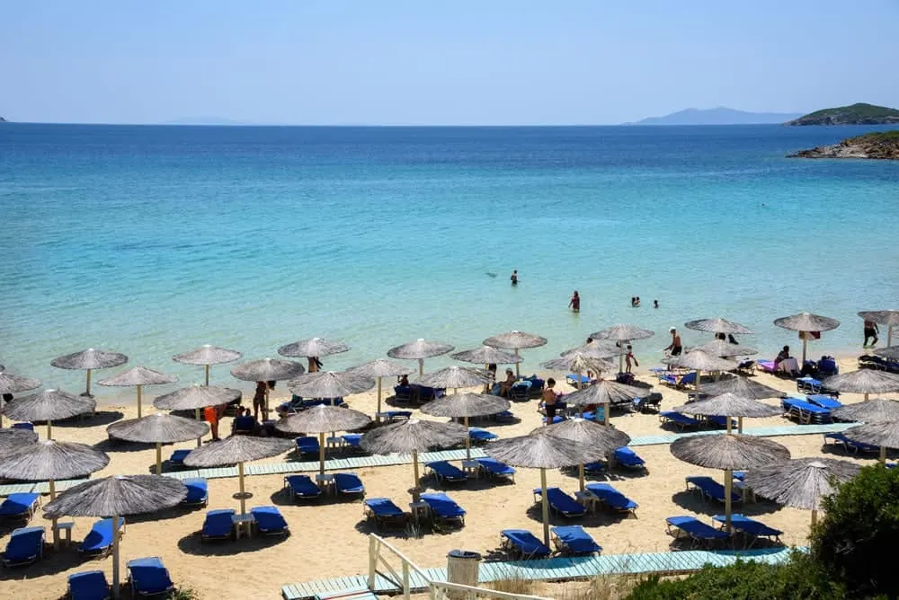 beach umbrellas and blue ocean on a greek island, an anti theft beach bag will allow you to relax while in swimming.