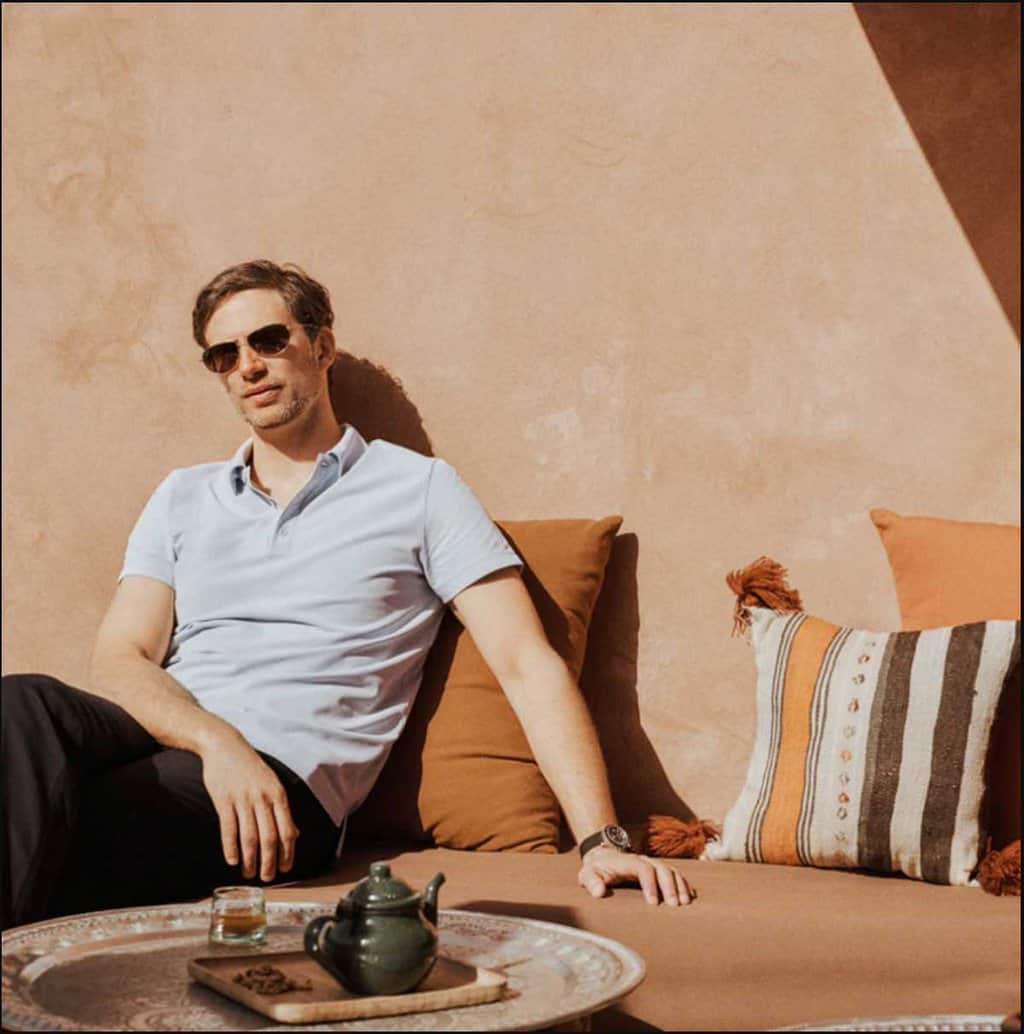 Man in a polo shirt having tea on a moroccan roof top. 