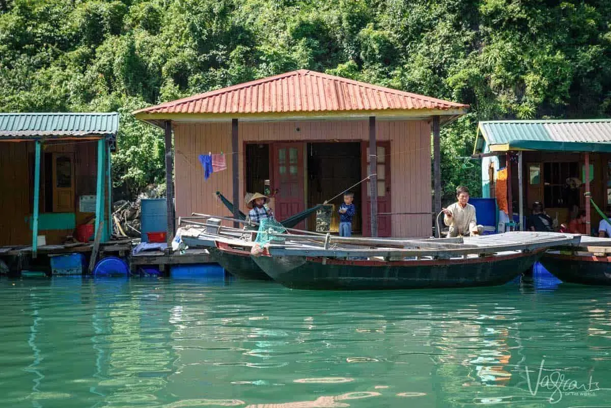 A family sit outside thier small wooden shack on the floating fishing village of Cua Van.