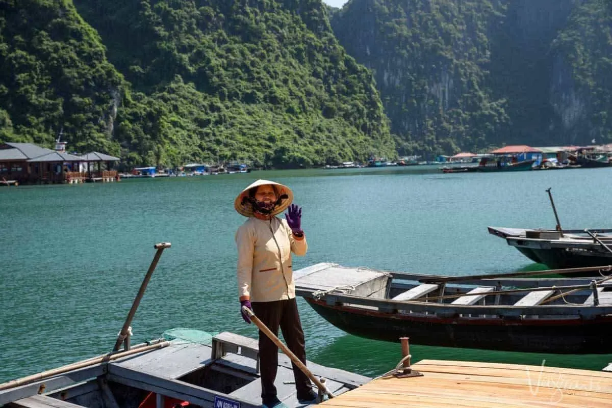 A Vietnamese woman in traditional dress waves from her boat in Cua Van Village in Halong Bay.