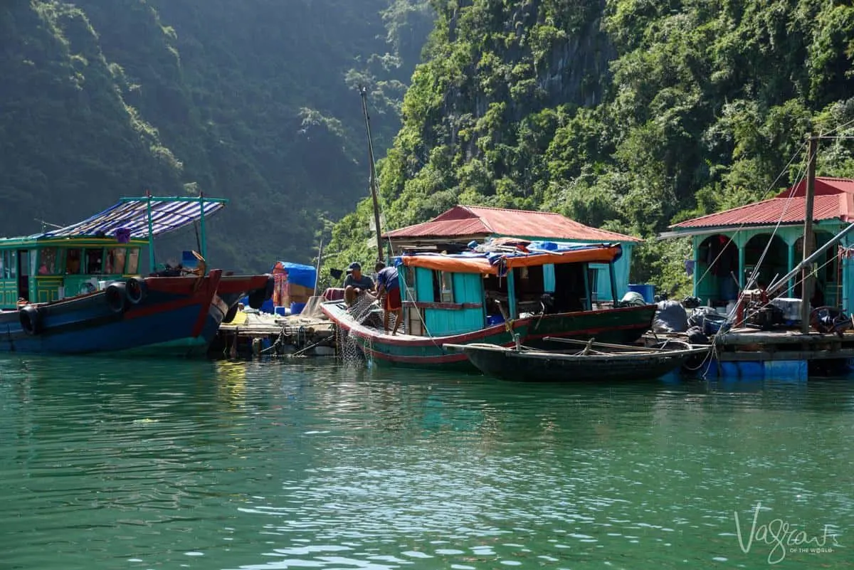 Locals tend the fishing nets on boats in a floating fishing village. 