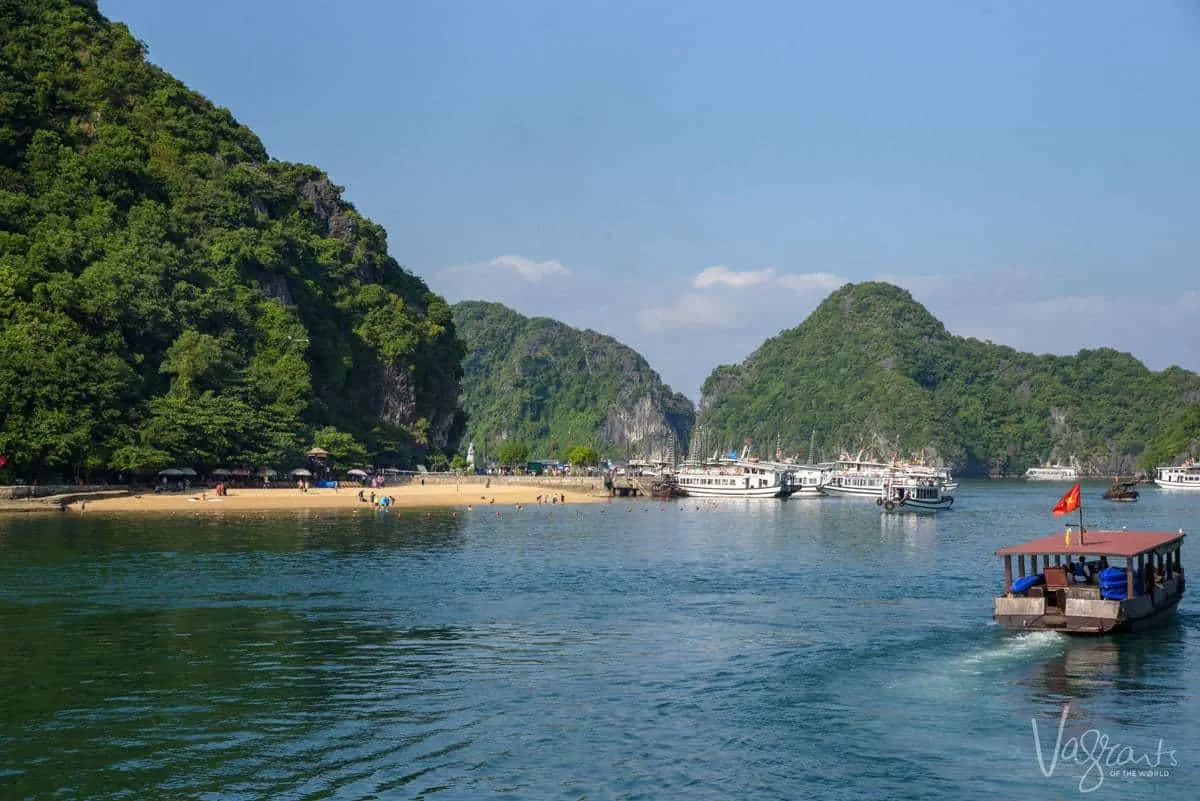 Boats dropping tourists off on Ti Top Beach in Halong Bay on a sunny day. 