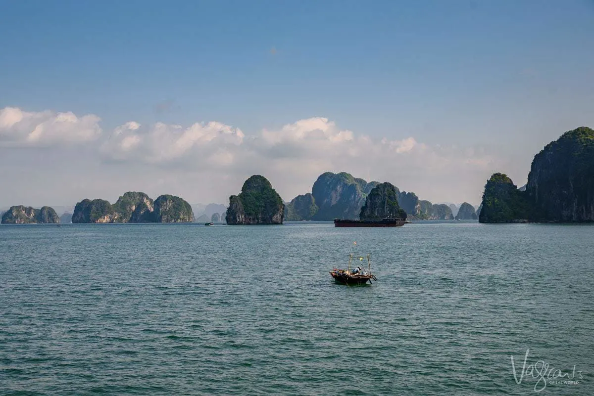 Fishing boat on Halong Bay with small rock islands scattered around the bay.