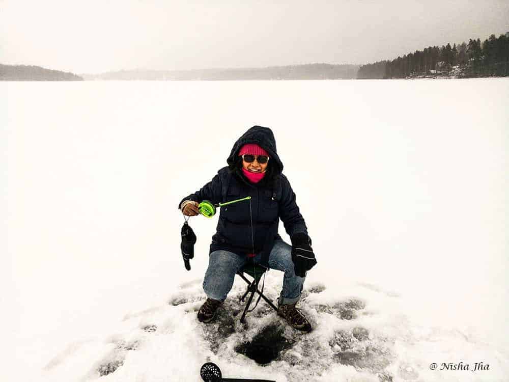 Lady sitting on a seat Ice fishing in Finland - Things to do in winter in Europe