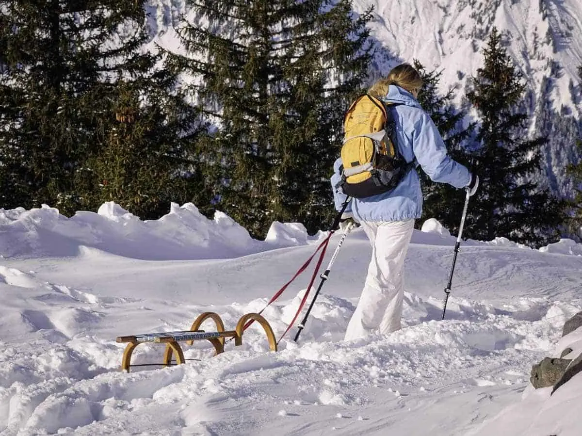 Tobogganing runs in Tyrol Austria are easily accessed on seperate walking tracks like this lady walking through the snow pulling her toboggan is using.