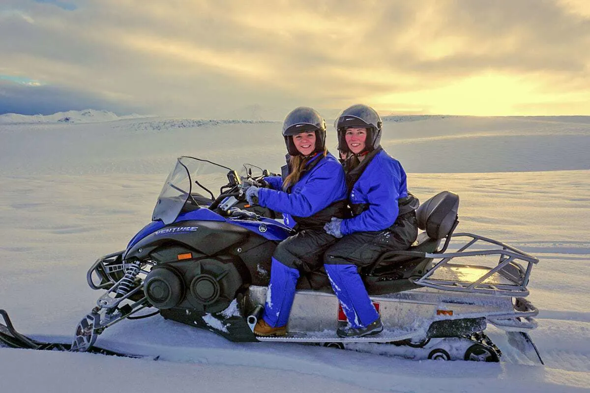 2 women sitting on a snowmobile in finland in winter - Activities to do in Finland in Winter