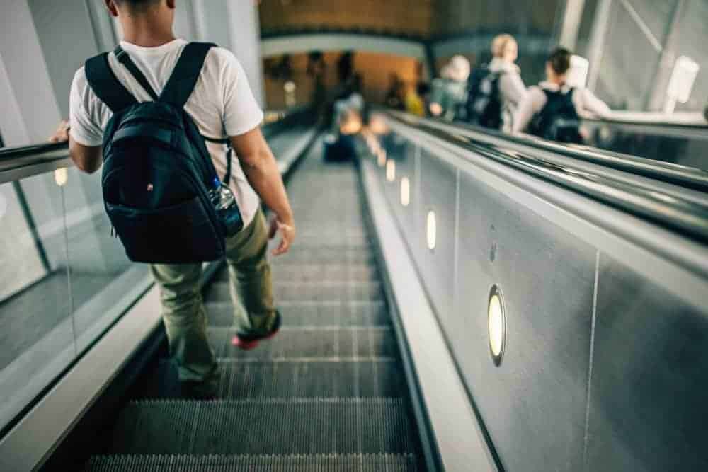 Best anti-theft backpack for travel. Man with backpack on escalator.