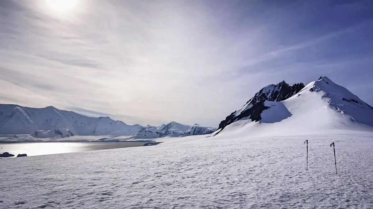 Antarctica ice and snow with 2 trekking poles on a sunny day.