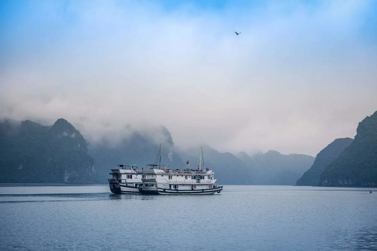 Winter cruise ship in Halong bay with beautiful fog drenched landscape.
